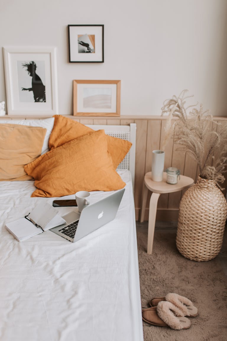 Empty bed with laptop and notebook