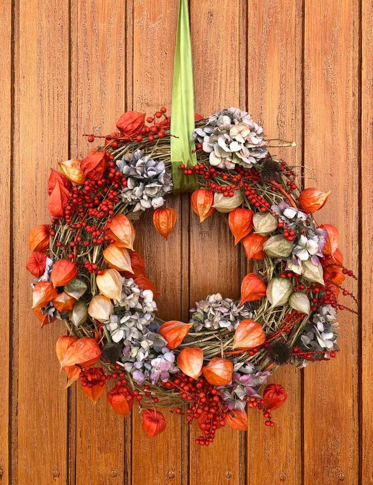 Colorful decorative wreath with autumn hues hanging on a wooden door.